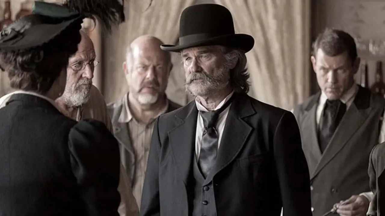 Kurt Russell como el sheriff Franklin Hunt con un sombrero derby y un esmoquin occidental negro en Bone Tomahawk. Kurt Russell como el sheriff Franklin Hunt con un sombrero derby y un esmoquin occidental negro en Bone Tomahawk.